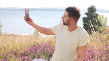 Doğada cep telefonundan selfie çeken bir adam..