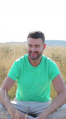 Genç yakışıklı bir adam tarlada oturuyor. 