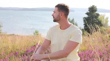Genç adam gölün yanındaki doğada dinleniyor.
