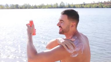 Genç erkek koruyucu güneş kremi kullanıyor.