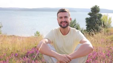 Genç adam gölün yanındaki doğada dinleniyor.