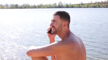 Gölün arkasında telefonla konuşan bir adam var.