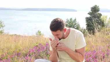 Çekici gömleksiz bir adam doğada sigara içiyor. 