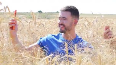 Sahada oturan mutlu adam akıllı telefon kullanıyor..