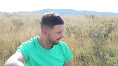 Dağların arka planında bir buket çiçekli genç adam.