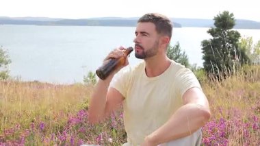 Yakışıklı adam şişeden bira içiyor.