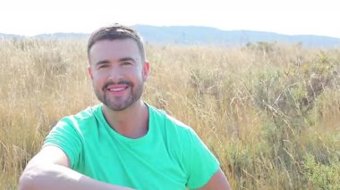 Bir buket çiçekle tarlada mutlu bir genç adam.