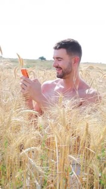 Sahada oturan mutlu adam akıllı telefon kullanıyor..