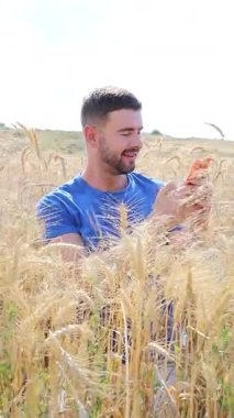 Sahada oturan mutlu adam akıllı telefon kullanıyor..