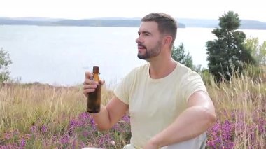 Yakışıklı adam şişeden bira içiyor.