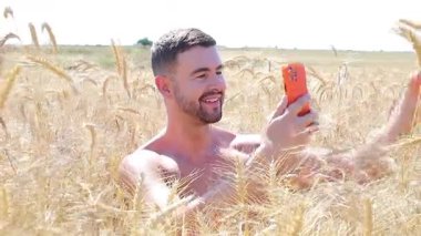 Sahada oturan mutlu adam akıllı telefon kullanıyor..