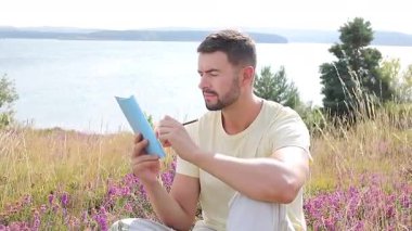 Buğday tarlasında defteri olan mutlu adam, yaz günü.