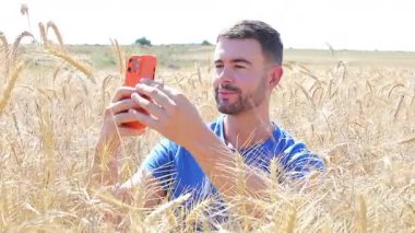 Sahada oturan mutlu adam akıllı telefon kullanıyor..