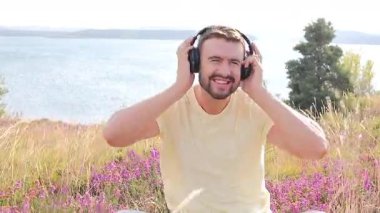 Doğada kulaklıkları olan yakışıklı genç bir adam.