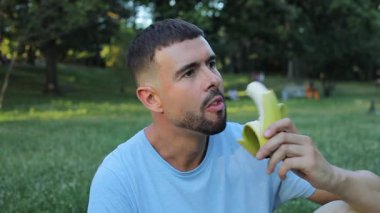 Yeşil arka planda muz yiyen bir adam