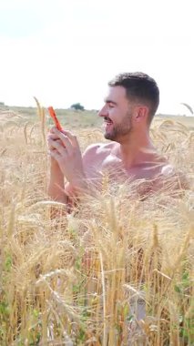 Sahada oturan mutlu adam akıllı telefon kullanıyor..