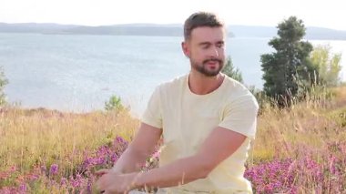 Dağlardaki çayırlarda bir adam Çiçekler ve gölle