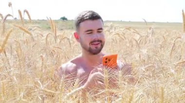 Sahada oturan mutlu adam akıllı telefon kullanıyor..