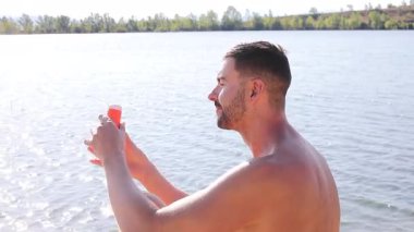 Genç erkek koruyucu güneş kremi kullanıyor.