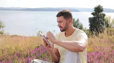 Buğday tarlasında defteri olan mutlu adam, yaz günü.