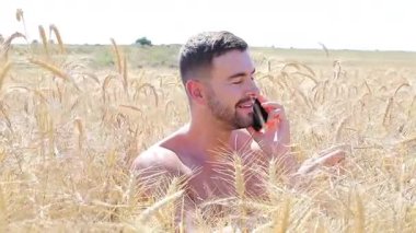 Sahada oturan mutlu adam akıllı telefon kullanıyor..