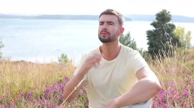  Genç adam parmaklarıyla Büyük Göl kıyısında Çimenli bir arazide dua ediyor..