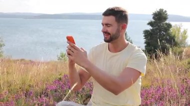 Sahada otururken selfie çeken mutlu adam..