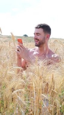 Sahada oturan mutlu adam akıllı telefon kullanıyor..