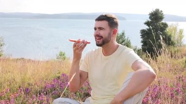 Gölün kenarındaki akıllı telefona konuşan yakışıklı adam.