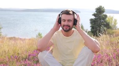 Doğada kulaklıkları olan yakışıklı genç bir adam.