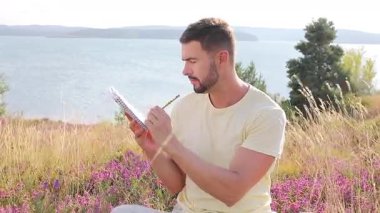 Buğday tarlasında defteri olan mutlu adam, yaz günü.