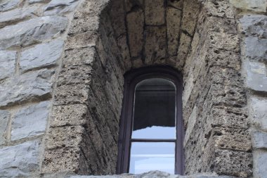 A close-up view of a beautifully arched window embedded in a textured stone wall, revealing the intricate details of historic architecture and natural light. clipart