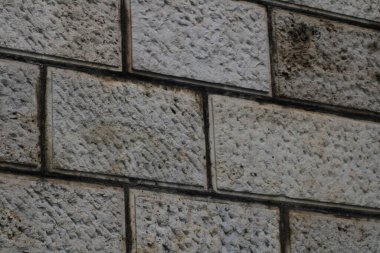 A textured stone wall features varying shades of gray and beige, with distinct patterns and surface details highlighted by the natural light of day. clipart