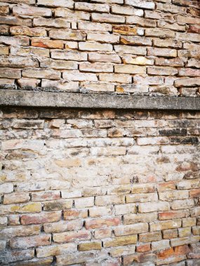 A well-worn brick wall displays a mix of earthy colors and textures, showcasing signs of age and weathering in an urban environment, creating a rustic backdrop. clipart