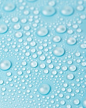 Su damlaları mavi arka planda, yakın planda.