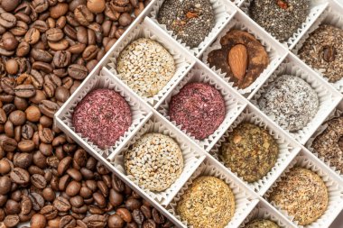 Kurutulmuş meyvelerden yapılmış beyaz bir kutuda şekerler, şekersiz ve boyasız. Doğal malzemelerden. İçinde hurma, hindistan cevizi, kurutulmuş kayısı, badem, fıstık, incir, susam ve kakao var..