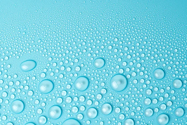 Su damlaları mavi arka planda, yakın planda.