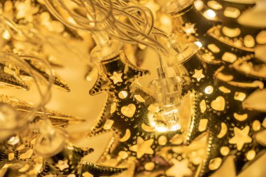 Altın Noel ağacı şeklinde parıldayan pullar ve çelenkler, süsleri ve figürleri olan, Noel konsepti. Sıcak ve lamba ortamı