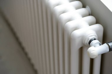 Bir adamın eli ısıtma termostat düğmesini tutuyor. Isıtma hizmetlerinin maliyeti, kamu hizmetlerinin fiyatlarındaki artış