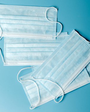 Mavi arka planda tıbbi koruyucu maske, koronavirüs önleme, virüs koruma faktörü. Tıbbi ya da cerrahi yüz maskesi. Virüs koruması. Solunum maskesi.