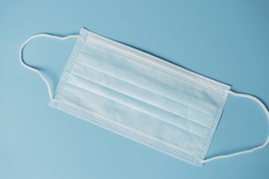 Mavi arka planda tıbbi koruyucu maske, koronavirüs önleme, virüs koruma faktörü. Tıbbi ya da cerrahi yüz maskesi. Virüs koruması. Solunum maskesi.