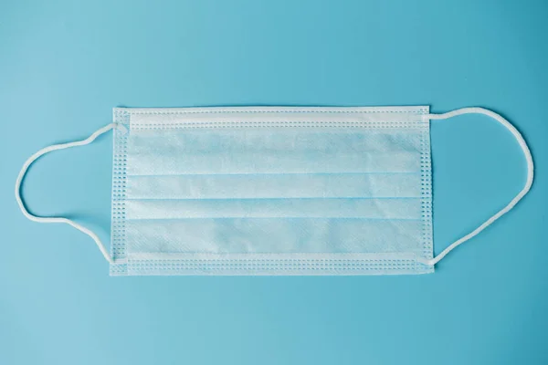 Medical protective mask on a blue background, coronavirus prevention, virus protection factor. Medical or surgical face mask. Virus protection. Respiratory respiratory mask.