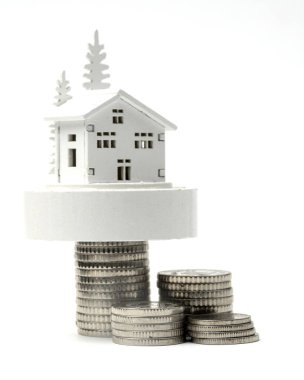 Bozuk paraların üzerinde mini bir ev. Yatırım gayrimenkul, borç verme, büyüme ve borç alma kavramı.