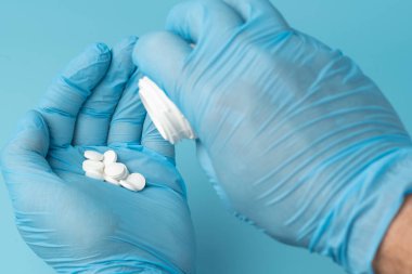 Doktorun elindeki haplar mavi arka planda.