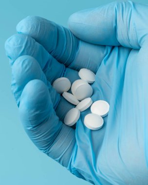 Doktorun elindeki haplar mavi arka planda.