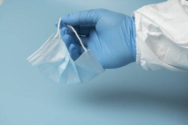 Mavi arka planda tıbbi koruyucu maske, koronavirüs önleme, virüs koruma faktörü. Tıbbi ya da cerrahi yüz maskesi. Virüs koruması. Solunum maskesi.