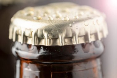 Kahverengi bir şişede soğuk bira ve cam yüzeyinde büyük su damlaları. Kara zanaat birası