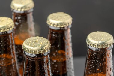 Kahverengi bir şişede soğuk bira ve cam yüzeyinde büyük su damlaları. Kara zanaat birası