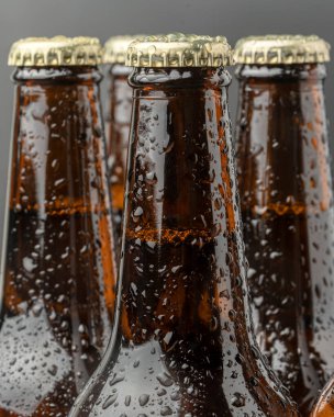 Kahverengi bir şişede soğuk bira ve cam yüzeyinde büyük su damlaları. Kara zanaat birası