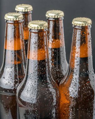 Kahverengi bir şişede soğuk bira ve cam yüzeyinde büyük su damlaları. Kara zanaat birası